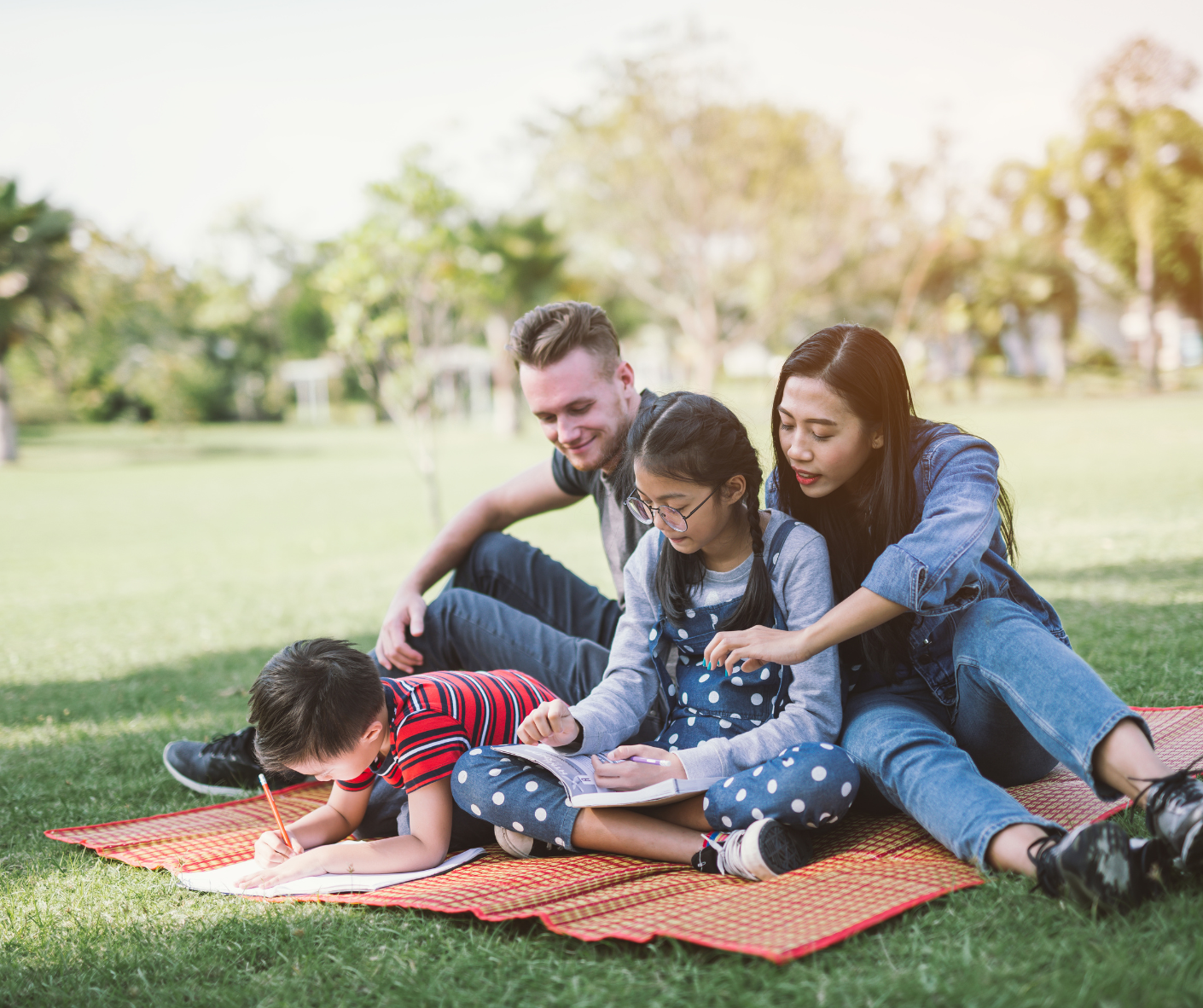 a family of 4 sitting in a park working on homework together